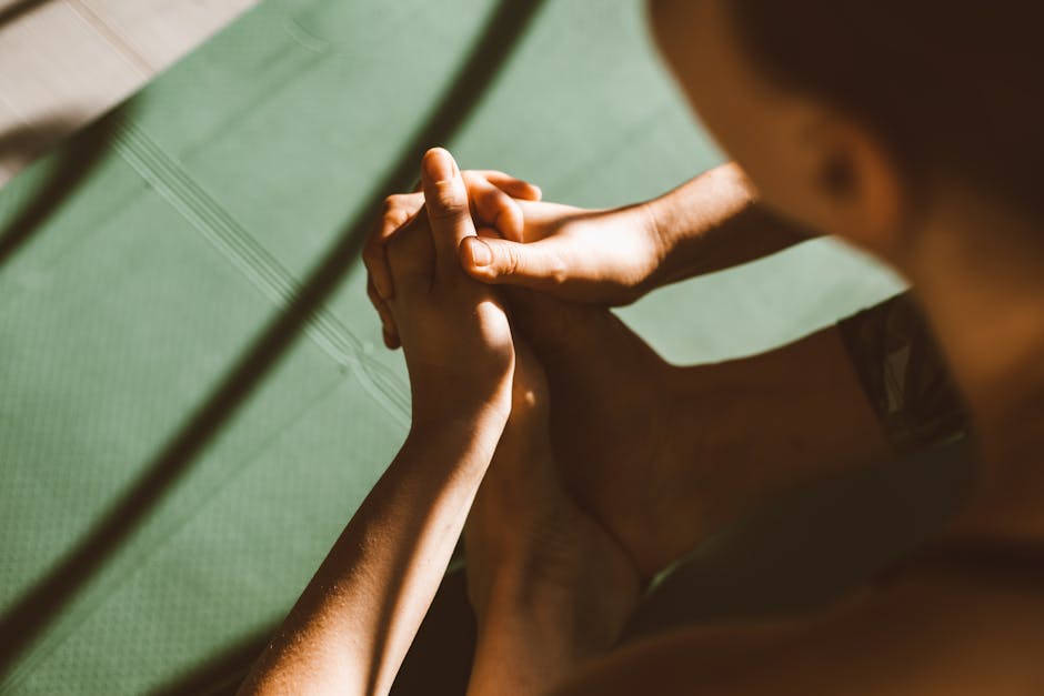 Close-up of a person on a yoga mat with hands in a thoughtful gesture.